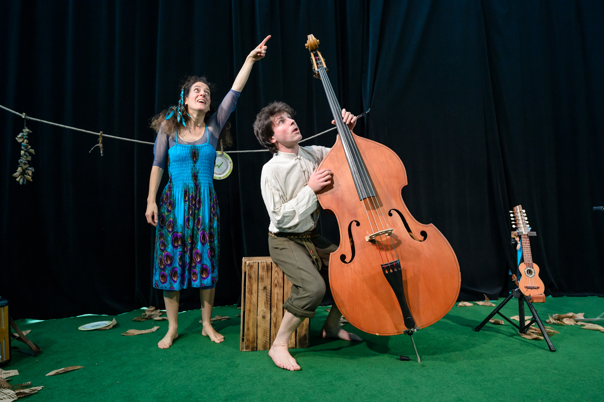 Cellist und Frau mit blauem Kleid entdecken etwas an der Decke