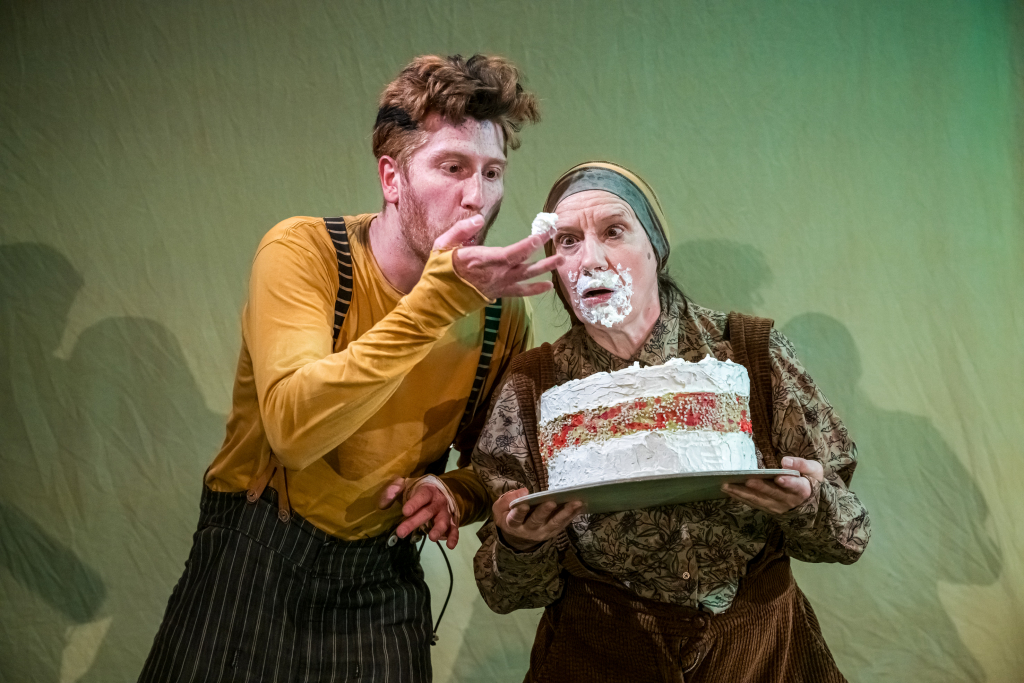 Zwei Schauspieler*innen: eine mit Torte in der Hand und Sahne im Gesicht und der andere hat Sahne am Finger.