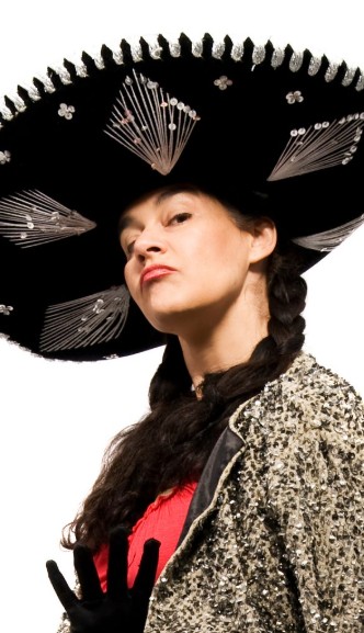 Frau mit großem, schwarzen Hut und glitzerndem Outfit.