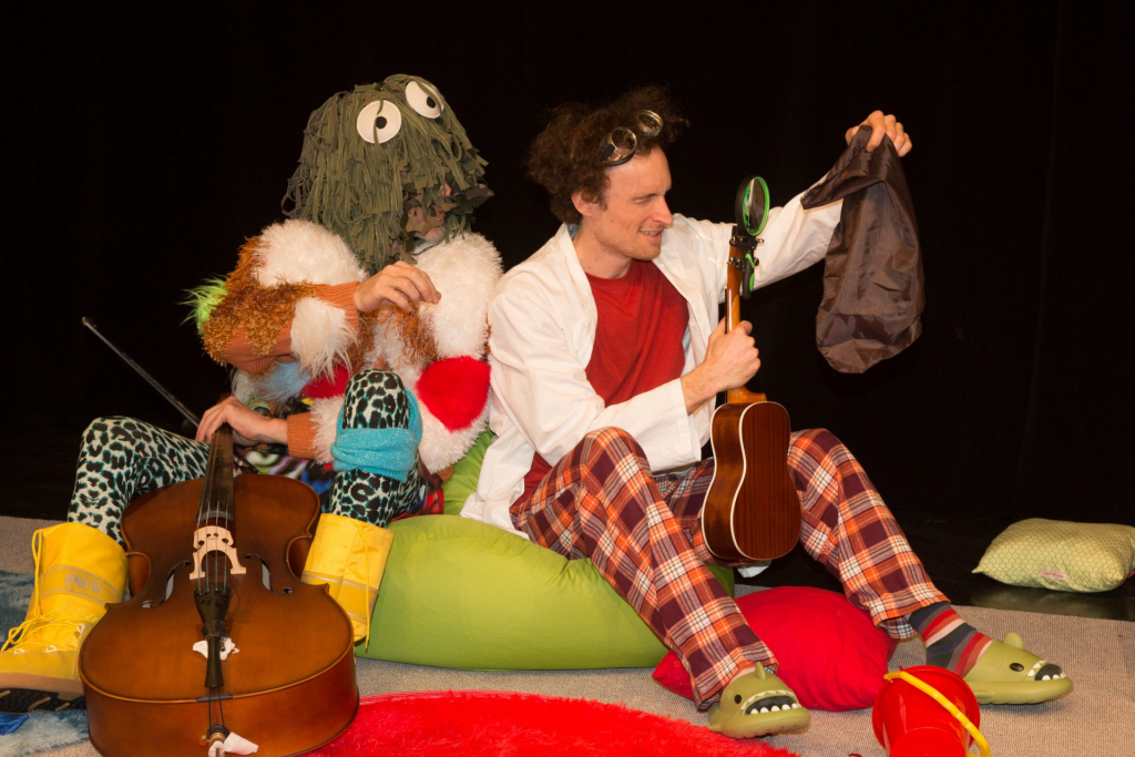 zwei Personen in bunten Kostümen, einer spielt Ukulele, der andere hat ein grünes Monsterkostüm.