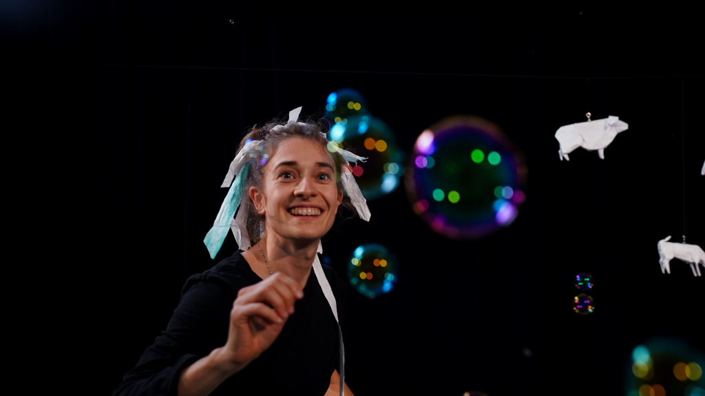 Frau mit weißen Bändern in den Haaren, lächelnd und spielend mit Seifenblasen.