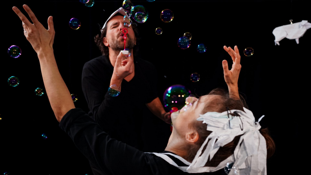 Mann und Frau erzeugen Seifenblasen mit einem Blasrohr