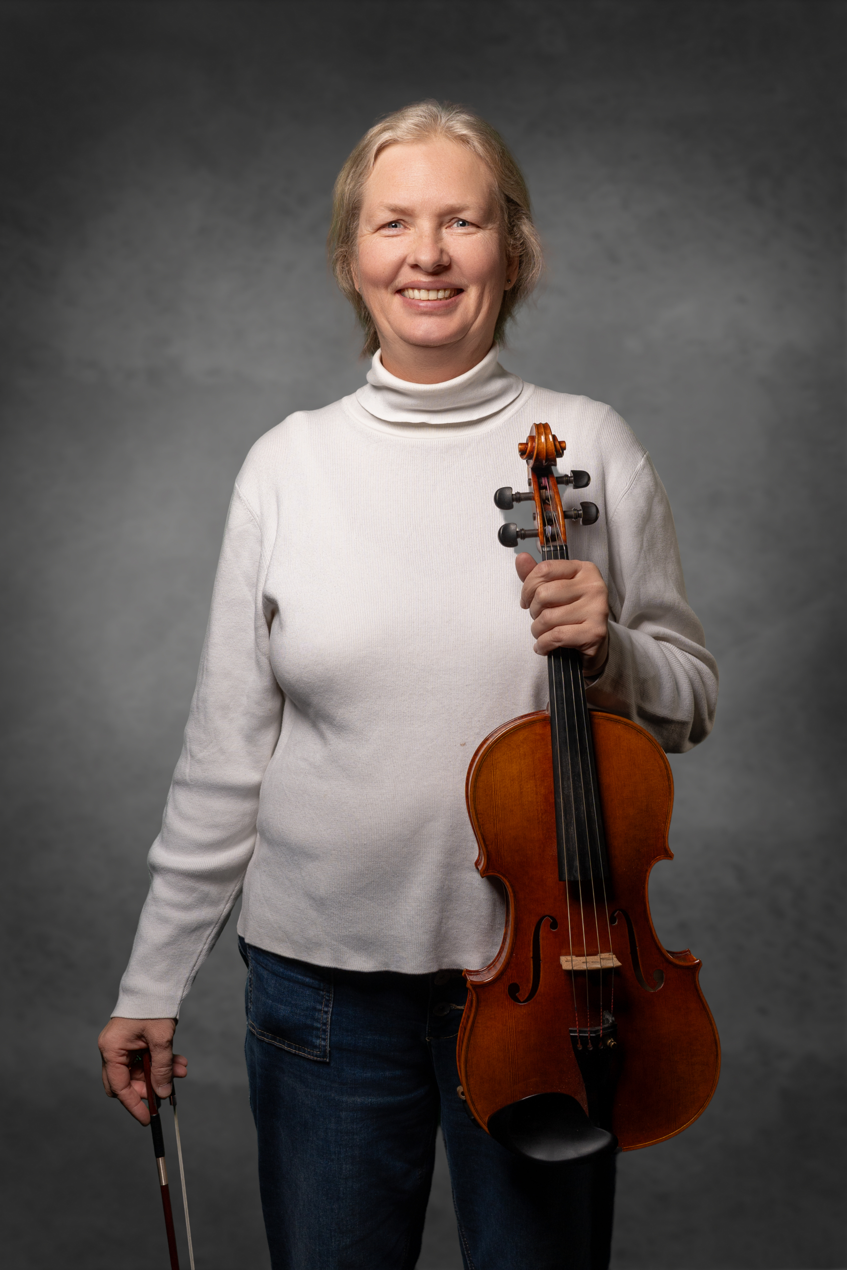 Frau in weißem Pullover hält eine Violine und einen Bogen für klassischen Musikunterricht.