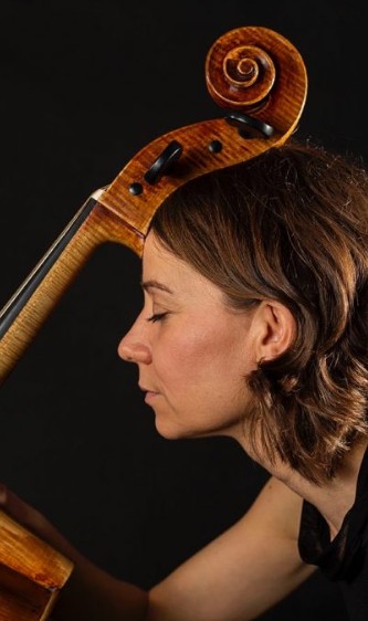 Porträt einer Frau mit Cello, Kopfneigung zur Cello-Öffnung, fokussierter Ausdruck.
