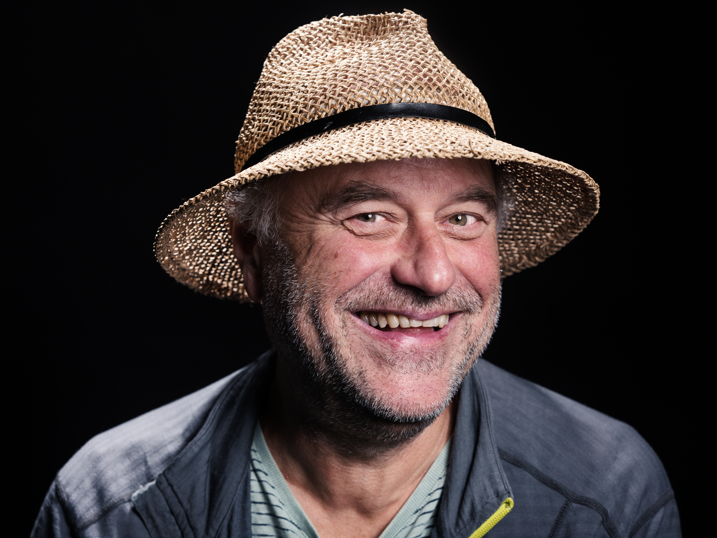 Lächelnder Mann mit Strohhut vor schwarzem Hintergrund