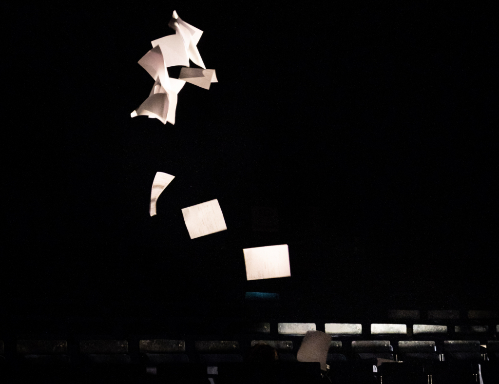 Leere, schwebende Zettel und Blätter auf schwarzem Hintergrund, die im Raum schweben.