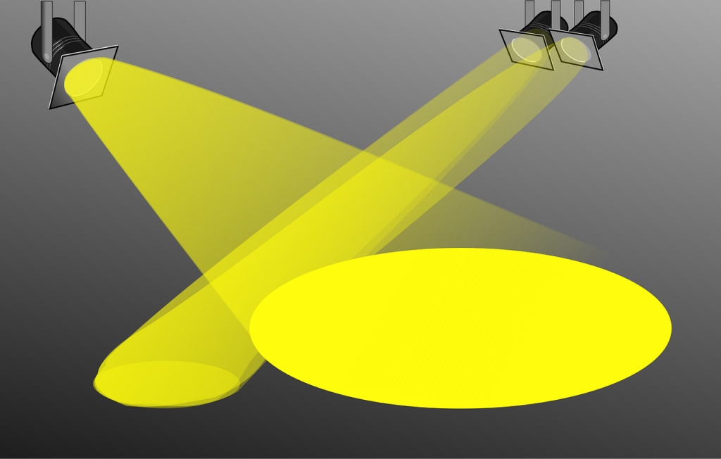 Scheinwerfer mit gelben Lichtstrahlen und einem gelben Lichtkreis auf einem grauen Hintergrund.